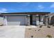 Charming single-story home with a two-car garage and a beautifully landscaped front yard under a clear sky at 18220 W Daley Ln, Surprise, AZ 85387