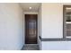 Inviting front entryway showcasing a sleek, dark-stained door, complemented by the textured exterior and framed window at 18220 W Daley Ln, Surprise, AZ 85387