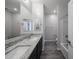 Bathroom featuring a double sink vanity with granite counters, tiled floors, and tub and shower at 18244 W Daley Ln, Surprise, AZ 85387