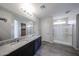 Bathroom featuring a double sink vanity with granite counters, tiled floors, and glass shower enclosure at 18244 W Daley Ln, Surprise, AZ 85387