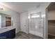 Bright bathroom features a glass shower with a bench, dark cabinets, and wood-look floors at 18244 W Daley Ln, Surprise, AZ 85387