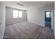Spacious bedroom with carpet, a large window, and a doorway that leads to an adjacent room at 18244 W Daley Ln, Surprise, AZ 85387
