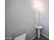 Clean powder room featuring a pedestal sink, toilet, mirror, and modern lighting at 18244 W Daley Ln, Surprise, AZ 85387