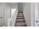 Carpeted staircase featuring a white railing offers a seamless transition between floors at 18244 W Daley Ln, Surprise, AZ 85387