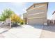 Two-story home with a tan stucco exterior, two-car garage, and low-maintenance desert landscaping at 1037 E Dust Devil Dr, San Tan Valley, AZ 85143
