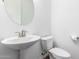 Compact half bathroom featuring a round mirror and pedestal sink at 11574 W Levi Dr, Avondale, AZ 85323