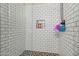 Detailed view of the shower featuring white tiling, pebble flooring, recessed shelf, and chrome shower head at 11732 W Foothill Dr, Sun City, AZ 85373