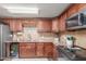 Kitchen featuring granite counters, brown cabinets, stainless steel appliances, and tile backsplash at 1620 N 72Nd Ln, Phoenix, AZ 85035