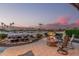 Backyard with a stone fire pit and chairs overlooking desert landscaping and palm trees at 16422 W Alvarado Dr, Goodyear, AZ 85395