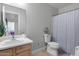 Well-lit bathroom with a clean sink, vanity, toilet and blue-striped shower curtain at 1673 S 218Th Ave, Buckeye, AZ 85326