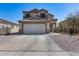 Two-story house with a two-car garage and a concrete driveway under a clear, blue sky at 1673 S 218Th Ave, Buckeye, AZ 85326