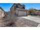 Exterior showcasing the home's tan facade, two-car garage, and concrete driveway, complemented by desert landscaping at 1673 S 218Th Ave, Buckeye, AZ 85326