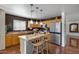 Kitchen with stainless steel appliances, wood cabinetry, pendant lights, and an island with seating at 1673 S 218Th Ave, Buckeye, AZ 85326