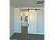 View from the bedroom through a sliding barn door into a bathroom with white cabinets at 22113 W Laura St, Wittmann, AZ 85361
