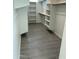 Spacious walk-in closet with white shelving and wood-look floors, offering ample storage at 22113 W Laura St, Wittmann, AZ 85361