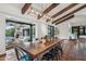 Dining room with exposed ceiling beams, terracotta tile flooring, modern light fixture, and large windows at 22402 N 84Th Pl, Scottsdale, AZ 85255