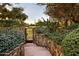 Stone stairway leading to a wrought iron gate, surrounded by lush greenery and mature trees, providing privacy at 22402 N 84Th Pl, Scottsdale, AZ 85255