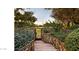 Stone stairway leading to a wrought iron gate, surrounded by lush greenery and mature trees, providing privacy at 22402 N 84Th Pl, Scottsdale, AZ 85255