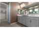 This bathroom features a double vanity with grey cabinets and a decorative mirror at 27629 N 176Th Dr, Surprise, AZ 85387