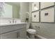 Stylish bathroom with a white vanity, decorative mirror, and textured wallpaper for added elegance at 27629 N 176Th Dr, Surprise, AZ 85387