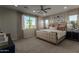This bedroom features an upholstered bed frame, a ceiling fan, and a large window providing natural light at 27629 N 176Th Dr, Surprise, AZ 85387