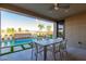 Covered patio with outdoor dining table overlooking a pool with waterfall feature and desert landscaping at 27629 N 176Th Dr, Surprise, AZ 85387
