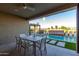 Covered patio featuring dining table, fan, and view of pool and decorative waterfall at 27629 N 176Th Dr, Surprise, AZ 85387