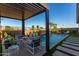 Backyard pool with pergola-covered seating area, waterfall feature, and lush desert landscaping at 27629 N 176Th Dr, Surprise, AZ 85387