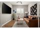 Comfortable living room featuring hardwood floors, a large TV, leather couch, and minimalist decor at 29854 N 132Nd Dr, Peoria, AZ 85383
