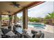 Covered outdoor living room has comfortable seating with views of pool and backyard at 29854 N 132Nd Dr, Peoria, AZ 85383