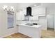 Bright kitchen features white cabinetry, modern black vent hood, and island with white countertop at 3326 E Calypso Ave, Mesa, AZ 85204