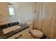 Well-maintained bathroom featuring a granite countertop, updated fixtures, and shower with patterned curtains at 4238 W Krall St, Phoenix, AZ 85019