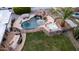 An aerial shot reveals a backyard pool with a slide and hot tub, complemented by lounge chairs, a grill, and verdant grass at 5642 E Justine Rd, Scottsdale, AZ 85254