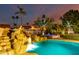 Backyard pool featuring rock waterfall and spa, surrounded by lush greenery and palm trees, creating a serene oasis at 5642 E Justine Rd, Scottsdale, AZ 85254