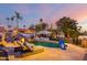 Twilight view of the backyard pool featuring a waterfall, lounge chairs, sun umbrella, and mature landscaping at 5642 E Justine Rd, Scottsdale, AZ 85254