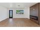 Bright living room with wood-look flooring, electric fireplace, modern accent wall, and a glass-paneled door at 7507 E Beatrice St, Scottsdale, AZ 85257