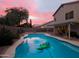 Backyard pool at dusk with colorful sky, covered patio, and privacy fence at 843 W Palo Verde St, Gilbert, AZ 85233