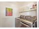 Modern laundry room featuring a front-loading washer and dryer, complemented by shelving and decorative artwork at 9070 E Gary Rd # 136, Scottsdale, AZ 85260