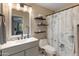 Bathroom with a vanity sink, toilet, and tub-shower combo with a stylish shower curtain, plus floating shelves at 927 W Wendy Way, Gilbert, AZ 85233