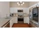 Well-lit kitchen boasts stainless steel appliances, white cabinets, granite countertops, and hardwood floors at 927 W Wendy Way, Gilbert, AZ 85233
