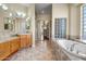 Bright bathroom with double sink vanity, soaking tub, and a glass block window for natural light at 12733 S 177Th Ln, Goodyear, AZ 85338