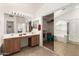 Bright bathroom featuring double sinks, wooden cabinetry, glass shower, and a spacious walk-in closet at 10322 E Excavation Ct, Gold Canyon, AZ 85118