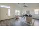 Bright living room featuring wood flooring, a ceiling fan, and sunlit windows at 11835 W Windsor Ave, Avondale, AZ 85392