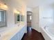 Bright bathroom featuring dual sinks, a soaking tub and wood look tile flooring at 14437 W Lexington Ave, Goodyear, AZ 85395