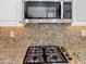 Close-up of the kitchen gas cooktop set against a decorative stone backsplash at 14437 W Lexington Ave, Goodyear, AZ 85395