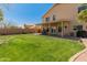 Lush green backyard featuring mature trees, desert landscaping, and a covered patio with outdoor seating at 15055 S 40Th Pl, Phoenix, AZ 85044