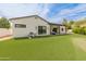 Large backyard with lush artificial grass, covered patio, and white exterior elevation at 1506 E Tuckey Ln, Phoenix, AZ 85014