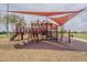 Community playground features a shade structure, climbing structures, slides, and a soft, impact-absorbing ground cover at 16526 W Calle Lejos --, Surprise, AZ 85387