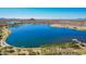Scenic aerial view of a serene lake surrounded by lush greenery and mountains at 17458 W Wandering Creek Rd, Goodyear, AZ 85338