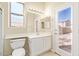 Bright bathroom with a toilet, sink and vanity, and a glass patio door leading to the exterior at 17458 W Wandering Creek Rd, Goodyear, AZ 85338